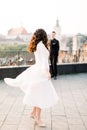 Young beautiful Asian bride in white wedding dress dancing on the terrace of ancient city. Groom standing on the Royalty Free Stock Photo
