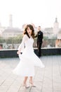 Young beautiful Asian bride in white wedding dress dancing on the terrace of ancient city. Groom standing on the Royalty Free Stock Photo