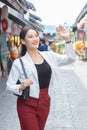 Young beautiful Asian business woman wear white suit and red pants smiling confidently,carry bag while walking in the city on a Royalty Free Stock Photo