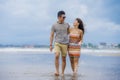 young beautiful and Asian Chinese romantic couple walking together embracing on the beach happy in love enjoying holidays Royalty Free Stock Photo