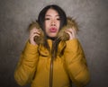 Young beautiful Asian Chinese woman feeling cold and chilly freezing feeling cold in Winter weather wearing yellow jacket with fur Royalty Free Stock Photo