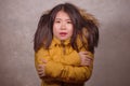 Young beautiful Asian Chinese woman feeling cold and chilly freezing feeling cold in Winter weather wearing yellow jacket with fur Royalty Free Stock Photo