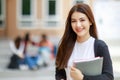 Young and beautiful Asian college student girls holding books, pose to camera with group of friends blur in background against Royalty Free Stock Photo