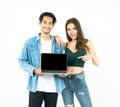 Young beautiful asian couple in fashion jeans shirts holding blank screen laptop computer for advertising while standing and Royalty Free Stock Photo