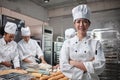 Young beautiful Asian female chef looks at camera, a cheerful smile in kitchen Royalty Free Stock Photo