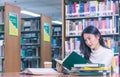 Young beautiful Asian female student portrait sitting and concentrate studying or reading textbook in university library for exams Royalty Free Stock Photo