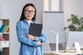 Young beautiful Asian female teacher looking at the camera and smiling, portrait of a woman in the office Royalty Free Stock Photo