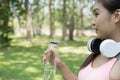 young beautiful asian fitness athlete woman holding drinking water after work out exercising at summer green park. Royalty Free Stock Photo