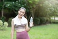 Young beautiful asian fitness woman holding bottle of water and relax after exercise, smiling and looking at camera. Copy space Royalty Free Stock Photo
