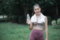 Young beautiful asian fitness woman holding bottle of water and relax after exercise, smiling and looking at camera. Copy space Royalty Free Stock Photo