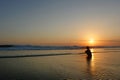 Young beautiful Asian girl alone at sea shore looking at orange sky sunset over ocean Royalty Free Stock Photo