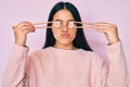 Young beautiful asian girl puting sushi on eyes using chopsticks looking at the camera blowing a kiss being lovely and sexy Royalty Free Stock Photo