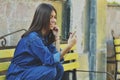 Young beautiful Asian girl looks sitting on a bench talking on the phone