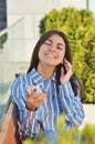 Young beautiful is asian girl sitts on the bench near green tress and listen to music Royalty Free Stock Photo