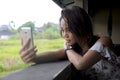 Young beautiful Asian girl taking selfie picture with mobile phone camera smiling happy sitting outdoors at coffee shop Royalty Free Stock Photo