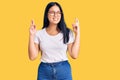 Young beautiful asian girl wearing casual clothes and glasses gesturing finger crossed smiling with hope and eyes closed Royalty Free Stock Photo