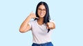 Young beautiful asian girl wearing casual clothes and glasses smiling doing talking on the telephone gesture and pointing to you Royalty Free Stock Photo