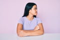 Young beautiful asian girl wearing casual clothes sitting on the table looking to side, relax profile pose with natural face with Royalty Free Stock Photo