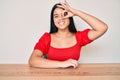 Young beautiful asian girl wearing casual clothes sitting on the table smiling happy doing ok sign with hand on eye looking Royalty Free Stock Photo