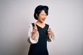 Young beautiful asian girl wearing casual dress and hat standing over isolated white background pointing fingers to camera with Royalty Free Stock Photo