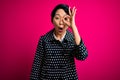 Young beautiful asian girl wearing casual jacket standing over isolated pink background doing ok gesture shocked with surprised Royalty Free Stock Photo