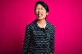 Young beautiful asian girl wearing casual jacket standing over isolated pink background sticking tongue out happy with funny Royalty Free Stock Photo