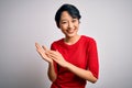 Young beautiful asian girl wearing casual red t-shirt standing over isolated white background clapping and applauding happy and Royalty Free Stock Photo