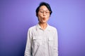 Young beautiful asian girl wearing casual shirt and glasses standing over purple background making fish face with lips, crazy and Royalty Free Stock Photo