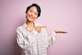 Young beautiful asian girl wearing casual shirt standing over isolated pink background amazed and smiling to the camera while Royalty Free Stock Photo