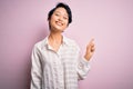Young beautiful asian girl wearing casual shirt standing over isolated pink background with a big smile on face, pointing with Royalty Free Stock Photo