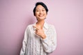 Young beautiful asian girl wearing casual shirt standing over isolated pink background cheerful with a smile on face pointing with Royalty Free Stock Photo