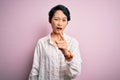 Young beautiful asian girl wearing casual shirt standing over isolated pink background pointing displeased and frustrated to the Royalty Free Stock Photo