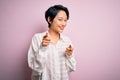Young beautiful asian girl wearing casual shirt standing over isolated pink background pointing fingers to camera with happy and Royalty Free Stock Photo