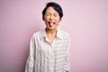 Young beautiful asian girl wearing casual shirt standing over isolated pink background sticking tongue out happy with funny Royalty Free Stock Photo