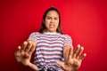 Young beautiful asian girl wearing casual striped t-shirt over isolated red background afraid and terrified with fear expression Royalty Free Stock Photo