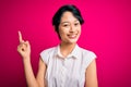 Young beautiful asian girl wearing casual summer shirt standing over isolated pink background with a big smile on face, pointing Royalty Free Stock Photo