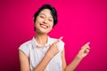 Young beautiful asian girl wearing casual summer shirt standing over isolated pink background smiling and looking at the camera Royalty Free Stock Photo