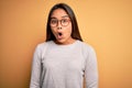 Young beautiful asian girl wearing casual sweater and glasses over yellow background afraid and shocked with surprise expression, Royalty Free Stock Photo
