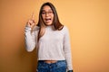 Young beautiful asian girl wearing casual sweater and glasses over yellow background pointing finger up with successful idea Royalty Free Stock Photo