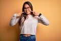 Young beautiful asian girl wearing casual sweater and glasses over yellow background smiling cheerful showing and pointing with Royalty Free Stock Photo