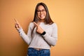 Young beautiful asian girl wearing casual sweater and glasses over yellow background smiling and looking at the camera pointing Royalty Free Stock Photo