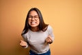 Young beautiful asian girl wearing casual sweater and glasses over yellow background very happy and excited doing winner gesture Royalty Free Stock Photo