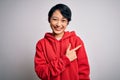 Young beautiful asian girl wearing casual sweatshirt with hoodie over white background cheerful with a smile of face pointing with Royalty Free Stock Photo