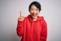 Young beautiful asian girl wearing casual sweatshirt with hoodie over white background pointing finger up with successful idea Royalty Free Stock Photo