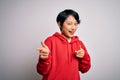 Young beautiful asian girl wearing casual sweatshirt with hoodie over white background pointing fingers to camera with happy and Royalty Free Stock Photo