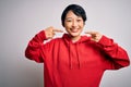 Young beautiful asian girl wearing casual sweatshirt with hoodie over white background smiling cheerful showing and pointing with Royalty Free Stock Photo