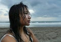 Young beautiful Asian girl with wet hair at sunset beach looking in the distance thoughtful and pensive
