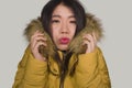 Young beautiful Asian Korean woman feeling cold and chilly freezing feeling cold in Winter weather wearing yellow jacket with fur Royalty Free Stock Photo