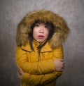 Young beautiful Asian Korean woman feeling cold and chilly freezing feeling cold in Winter weather wearing yellow jacket with fur Royalty Free Stock Photo