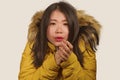 Young beautiful Asian Korean woman feeling cold and chilly freezing feeling cold in Winter weather wearing yellow jacket with fur Royalty Free Stock Photo